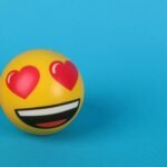 A cheerful heart eyes emoji stress ball resting on a vibrant blue background, symbolizing love and joy.